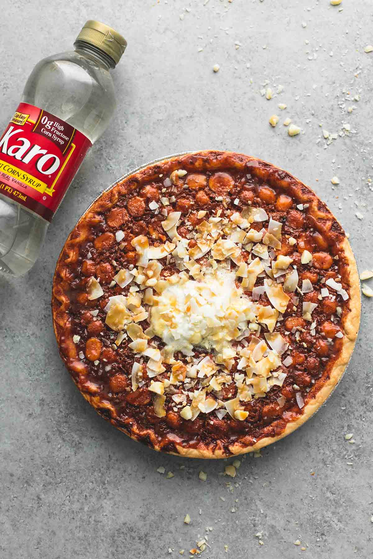 top view of a caramel coconut macadamia nut pie with a bottle of Karo corn syrup on the side.