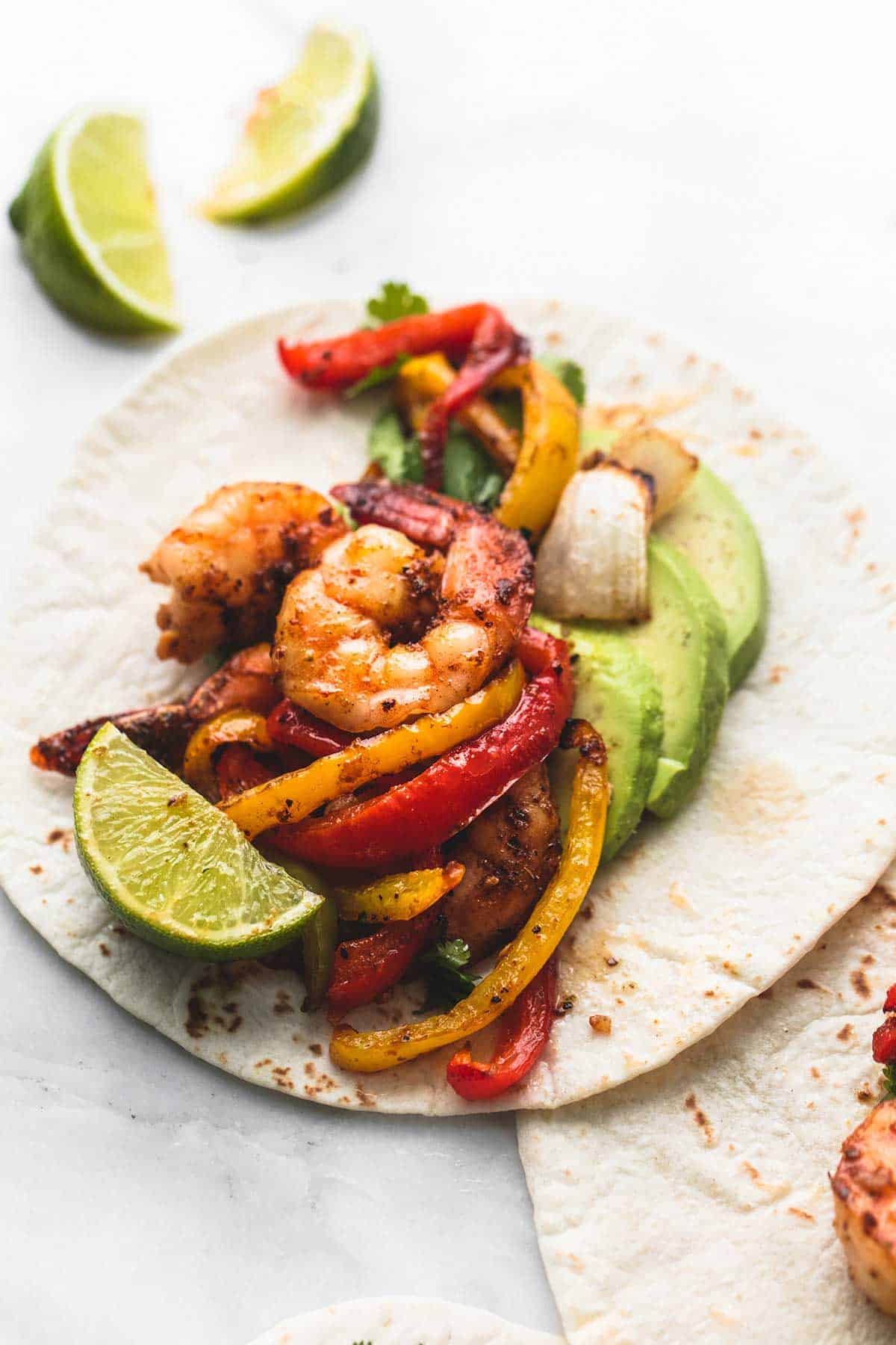 a Chili lime shrimp fajita with limes slices on the side.