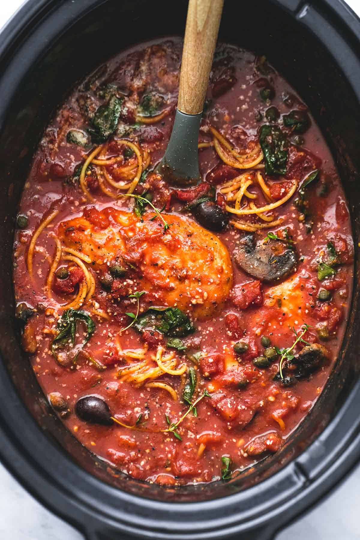 top view of slow cooker chicken cacciatore with a serving spoon in a slow cooker.