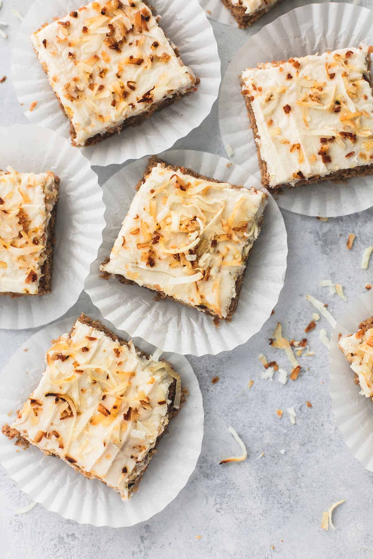 top view of carrot cake bars with coconut cream cheese frosting on cupcake liners.