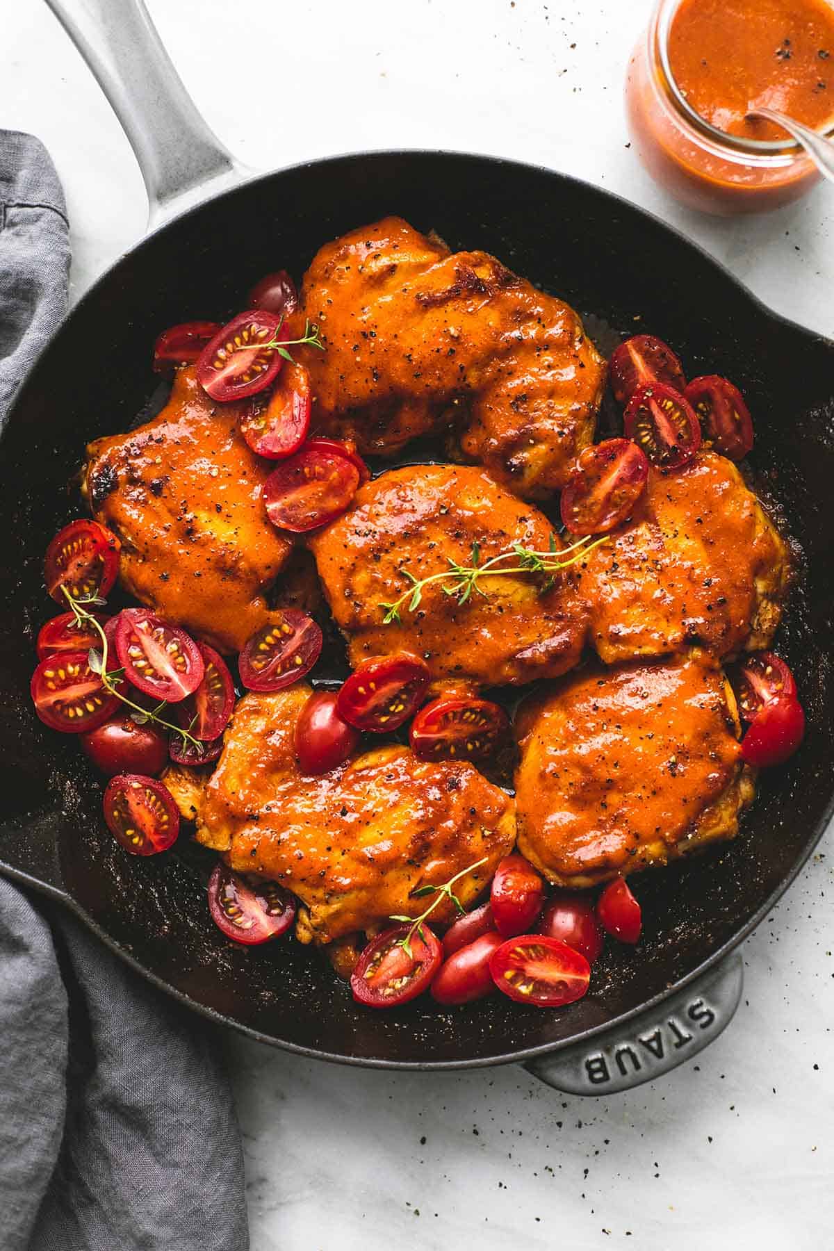 top view of Catalina chicken in a pan with sweet and tangy Catalina sauce with a spoon in a jar on the side.