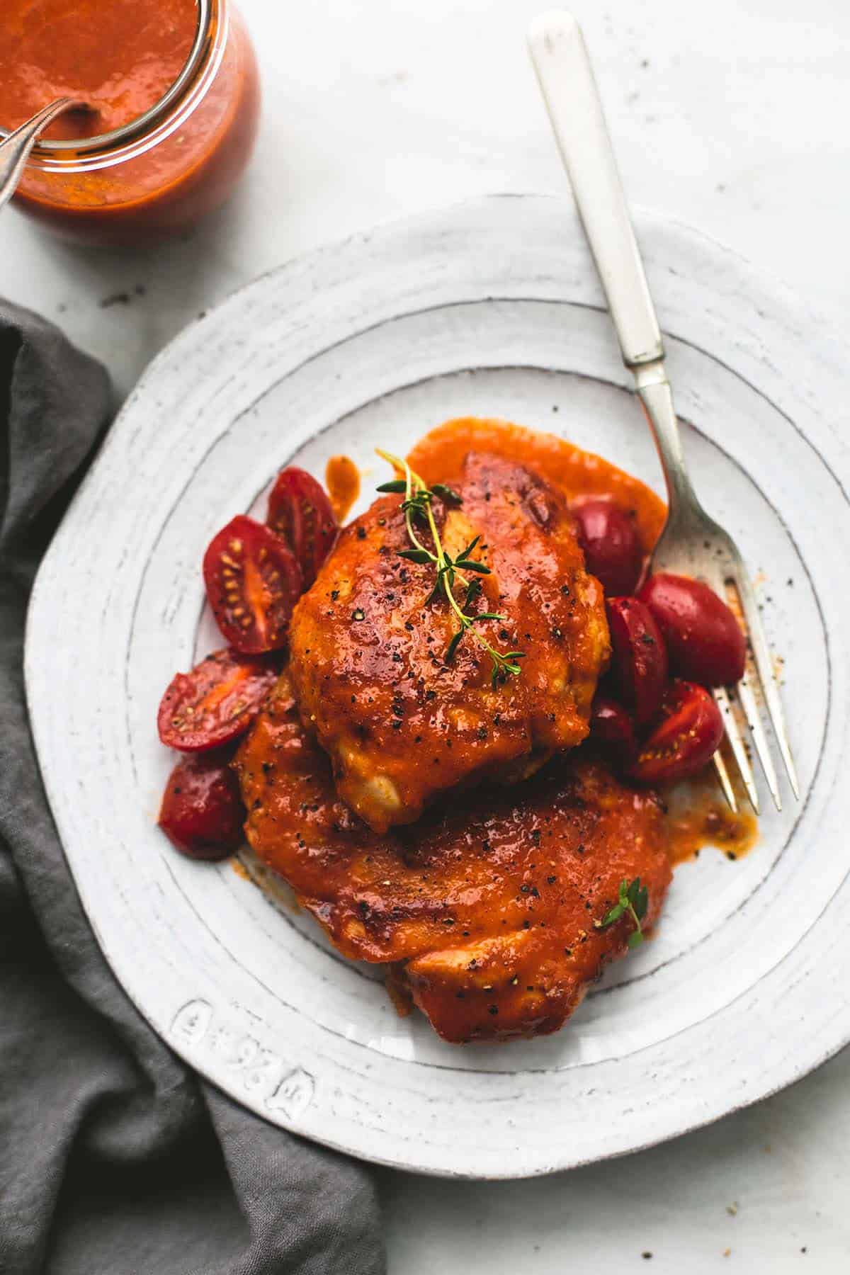 top view of Catalina chicken with a fork on a plate with a jar of sweet and tangy Catalina sauce with a spoon on the side.