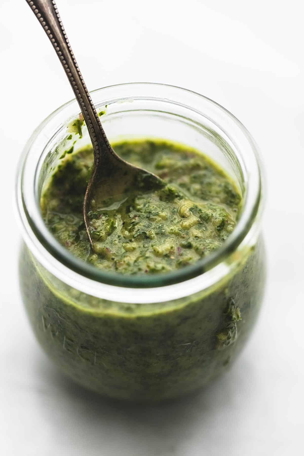a jar of chimichurri sauce with a spoon.