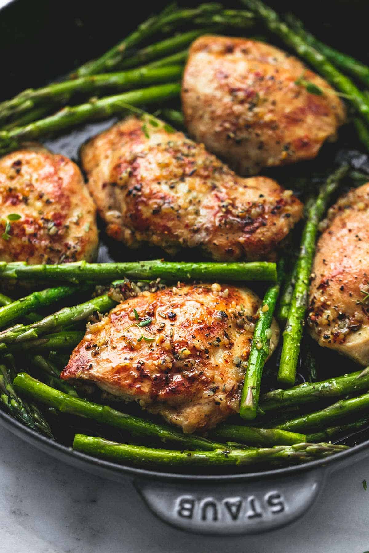 close up of garlic herb chicken and asparagus in a pan.