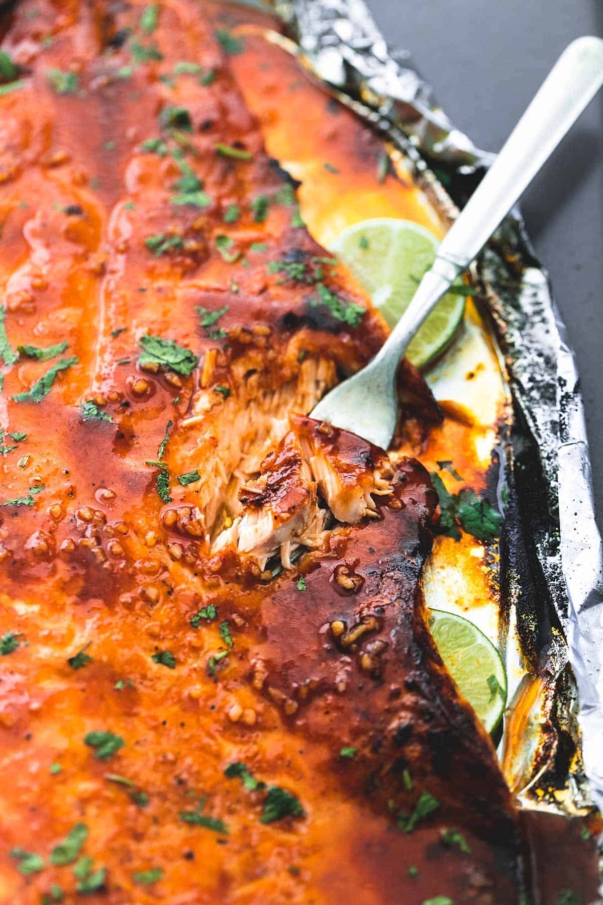 close up of baked honey sriracha lime salmon with a fork in it.