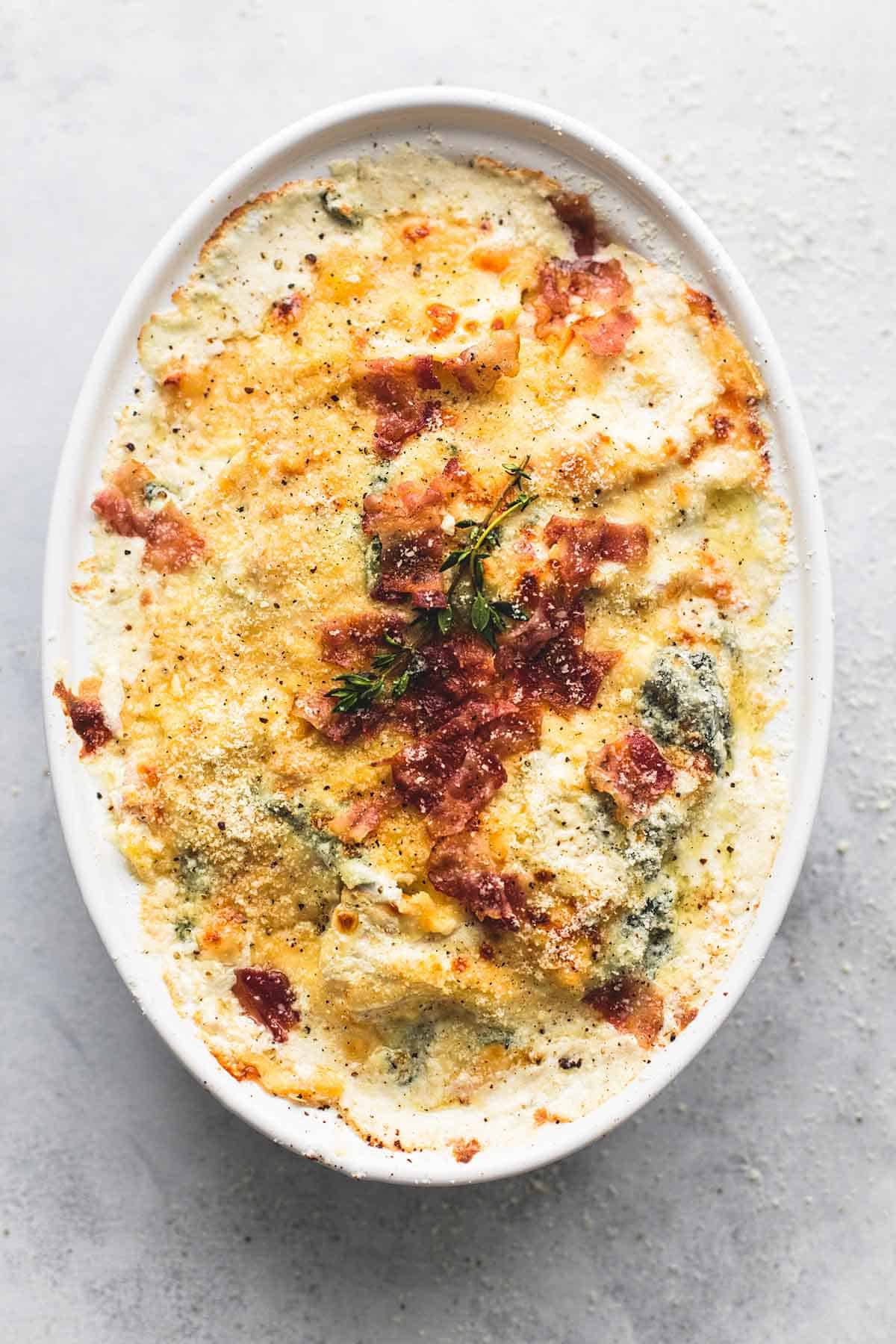 top view of ravioli alfredo bake with bacon and spinach in a serving tray.