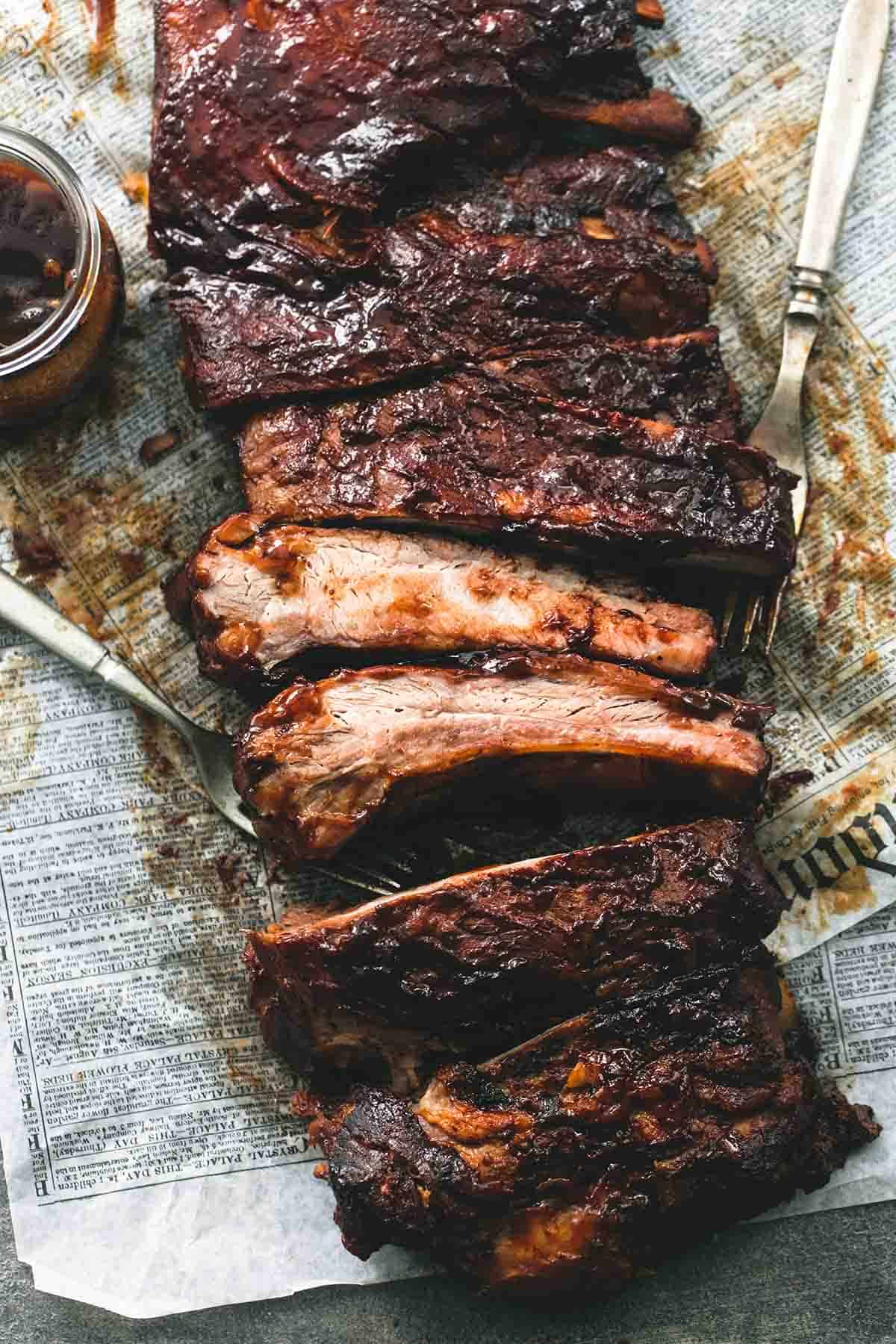 top view of slow cooker bbq ribs with forks and sauce on the side.