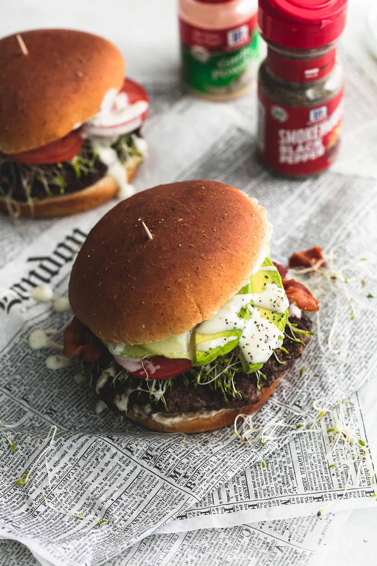 California club burgers with containers of spices on the side.