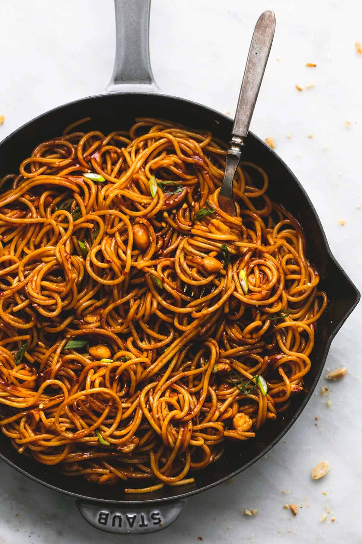 top view of kung pao noodles with a fork in a pan.