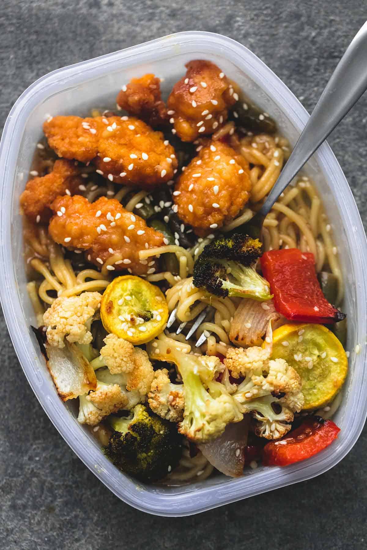 top view of roasted Asian vegetable medley in a serving tray with a fork and chicken.