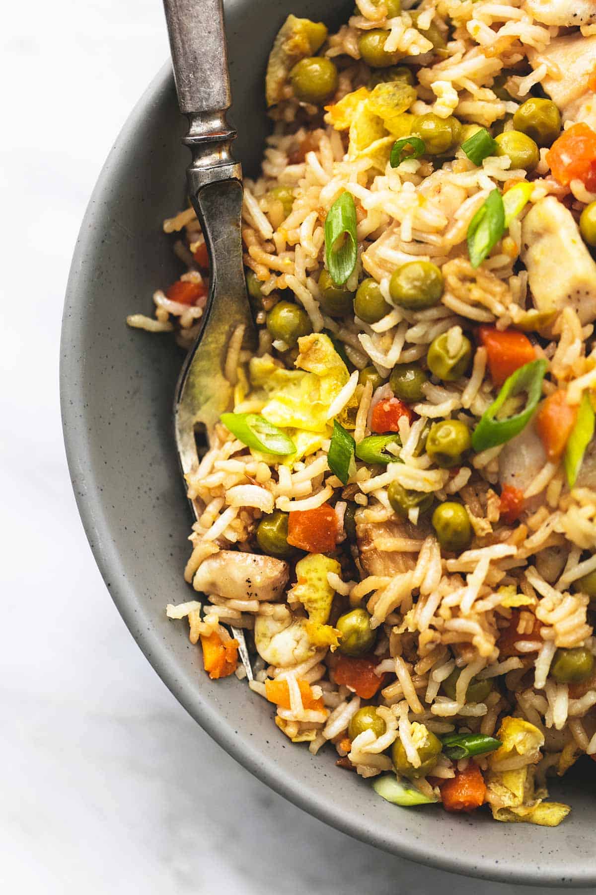 close up top view of sheet pan chicken fried rice with a fork in a bowl.