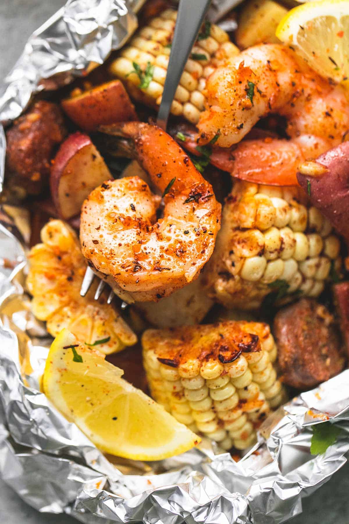 close up of a shrimp boil foil pack with a fork.