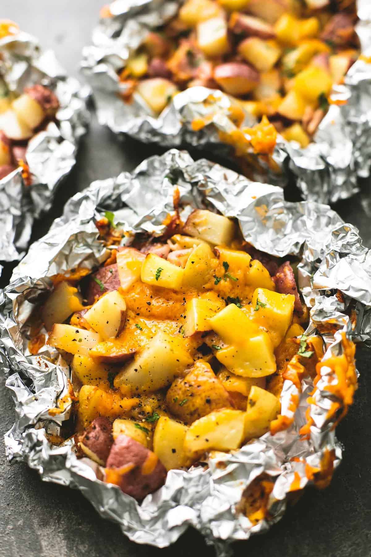 a bacon cheddar potatoes foil pack with more in the background.