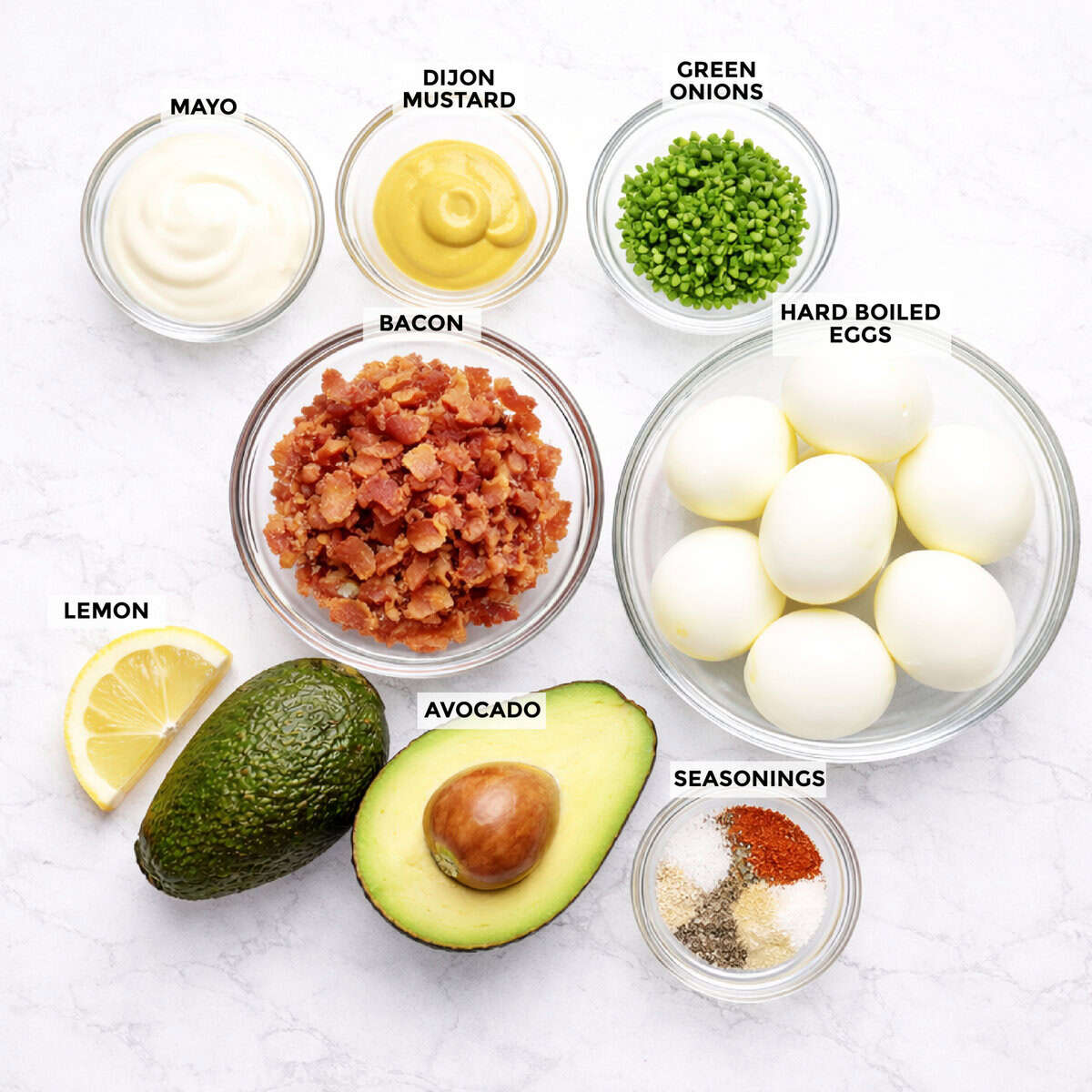 Ingredients for avocado and egg salad recipe on marble tabletop.