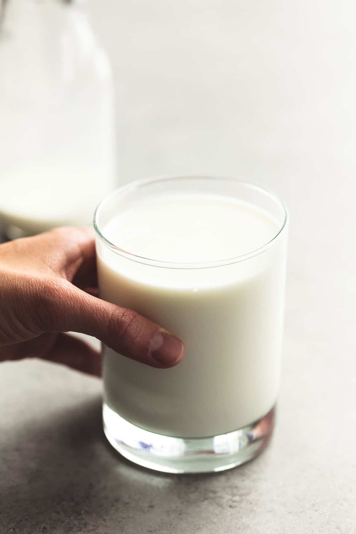 a hand holding a glass of milk.