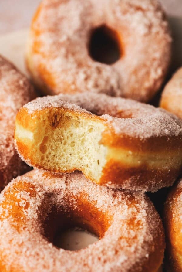 Close up of fried yeast donuts with a bite taken out of one.