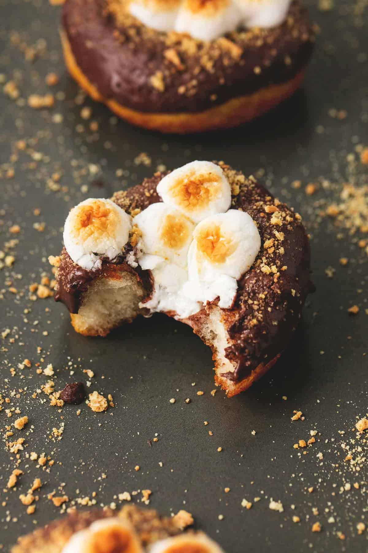 a s'mores donut with a bite missing with another donut in the background.