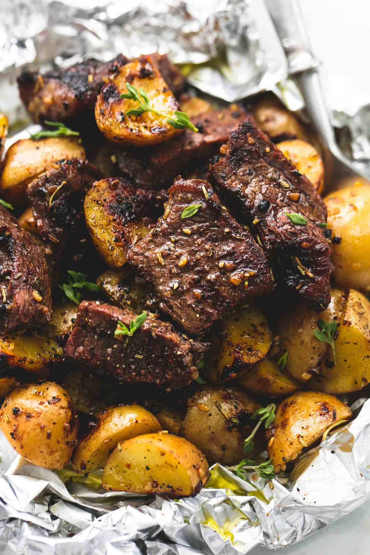 close up of a garlic steak and potato foil pack with a fork.