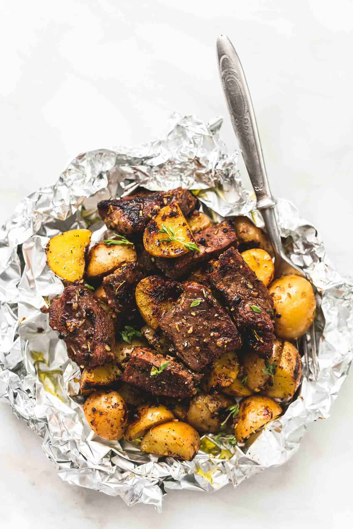 top view of a garlic steak and potato foil pack with a fork.