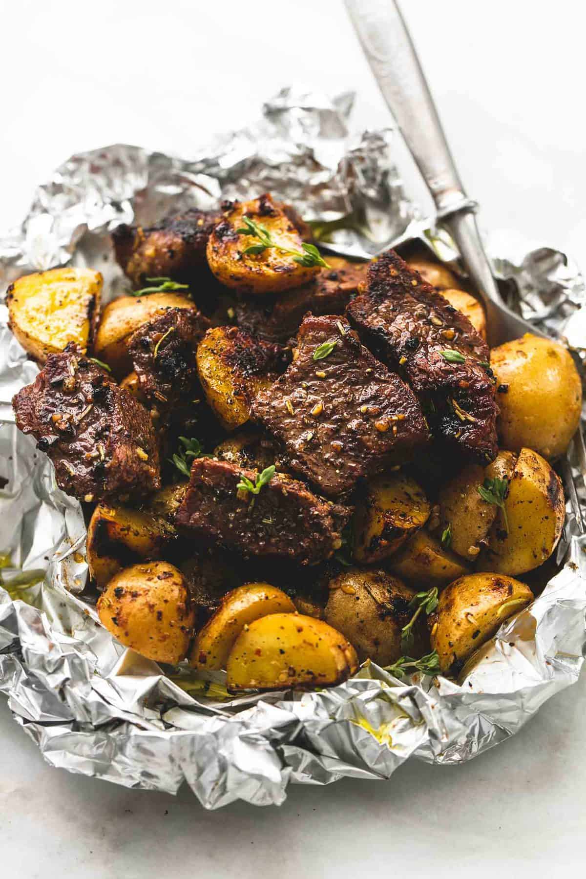 a garlic steak and potato foil pack with a fork.