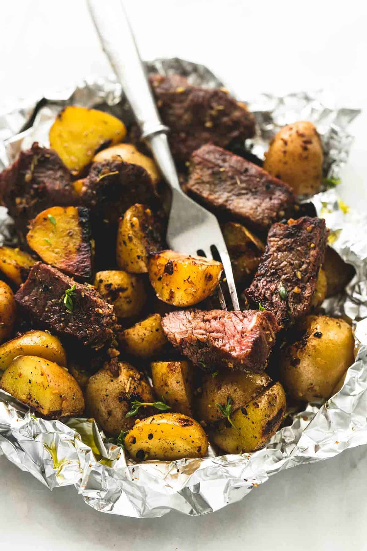 a garlic steak and potato foil pack with a fork.