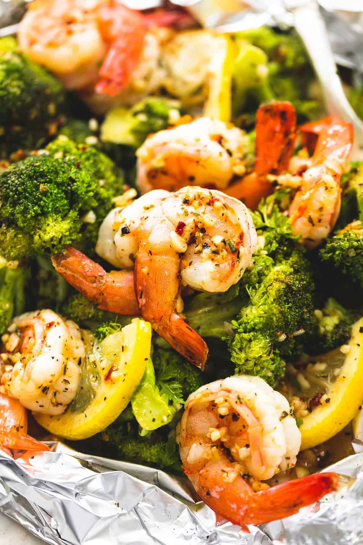 close up of a lemon herb shrimp and broccoli foil pack with a fork.