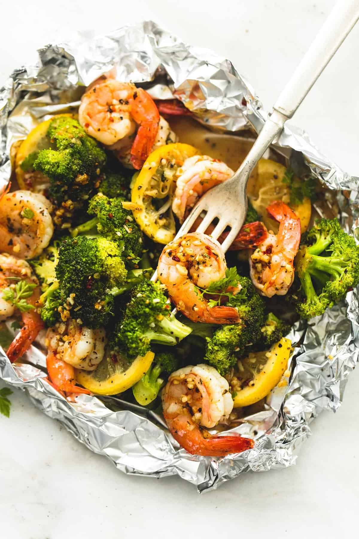 top view of a lemon herb shrimp and broccoli foil pack with a fork.