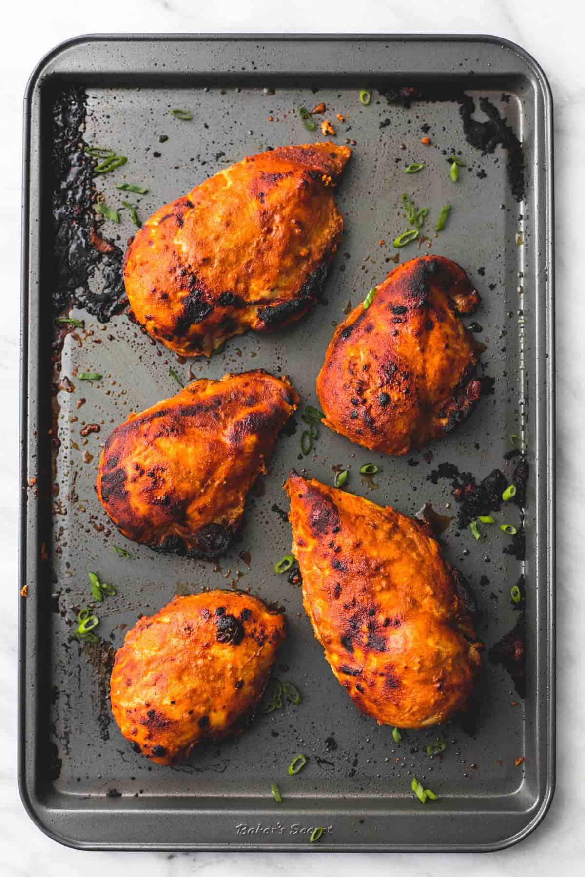 top view of baked tandoori chicken on a baking sheet.