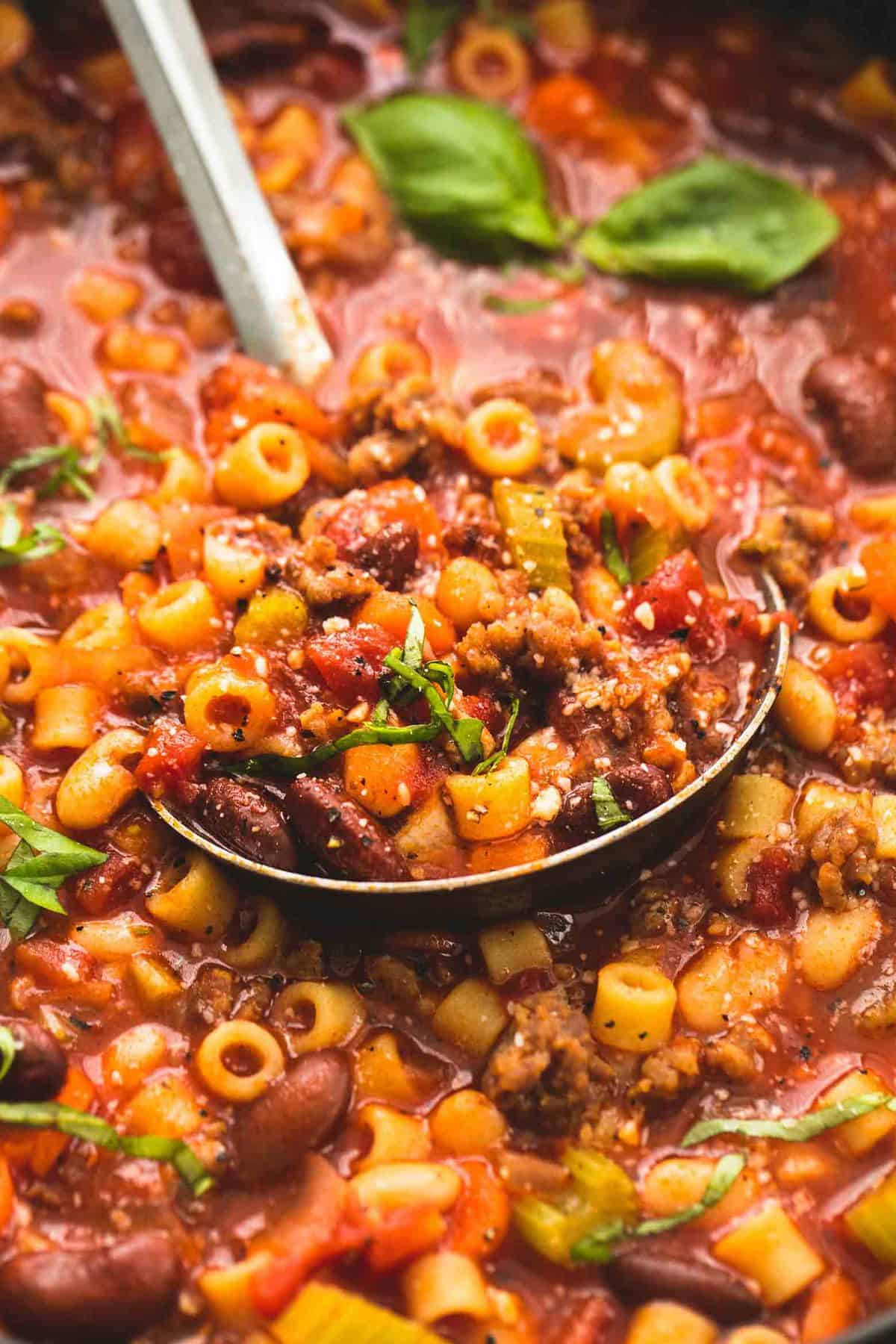 close up of pasta e fagioli soup and a serving spoon.