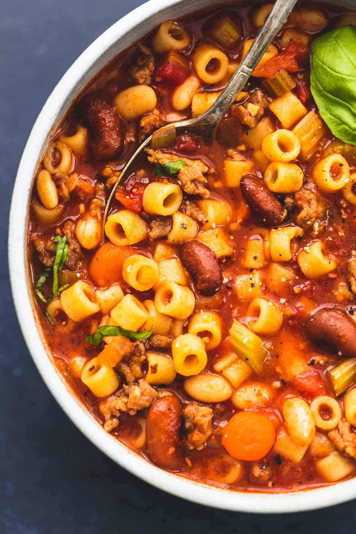 close up top view of pasta e fagioli soup with a spoon in a bowl.