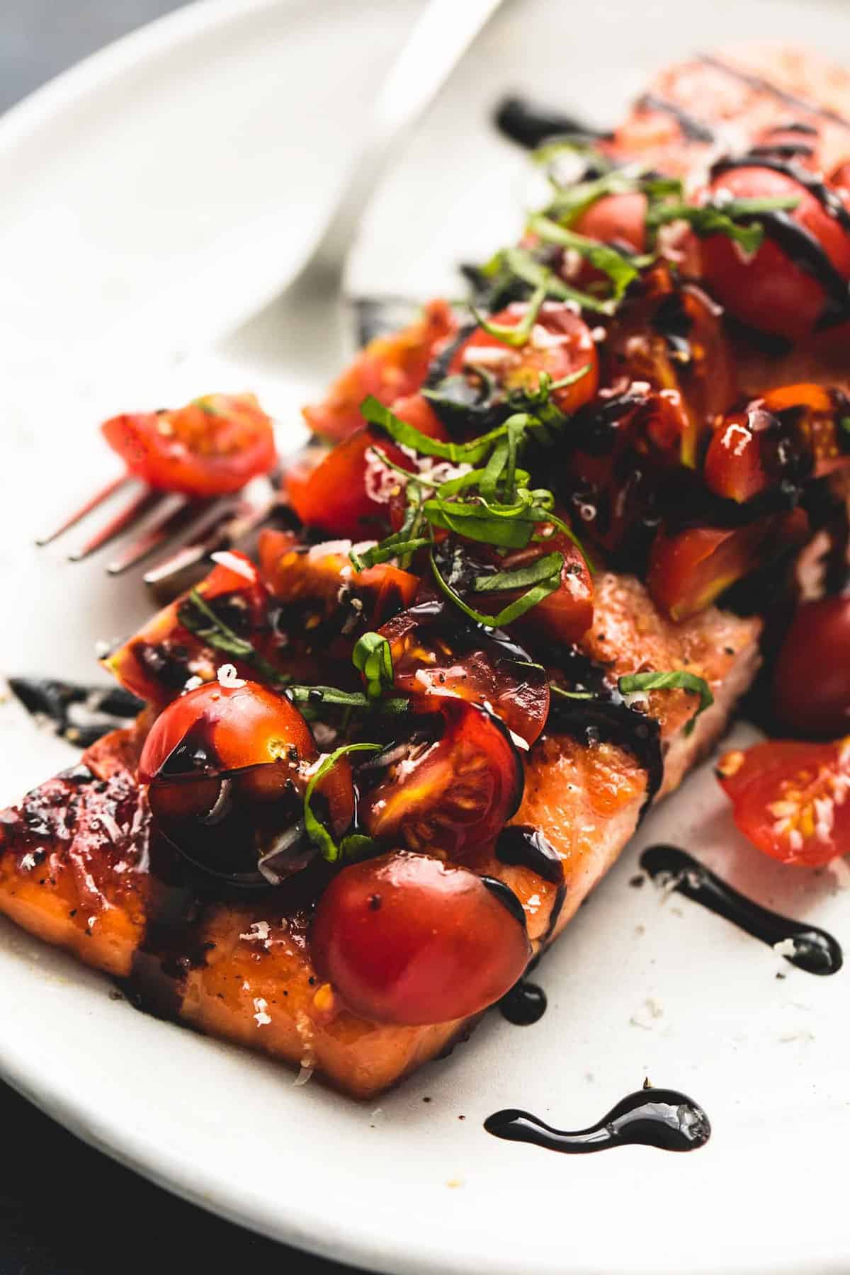 close up of honey balsamic bruschetta salmon with a fork on a plate.