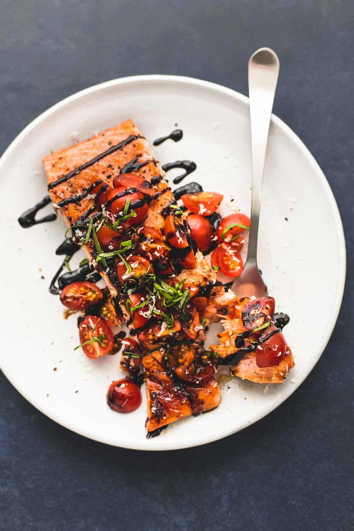 top view of honey balsamic bruschetta salmon with a bite on a fork on a plate.