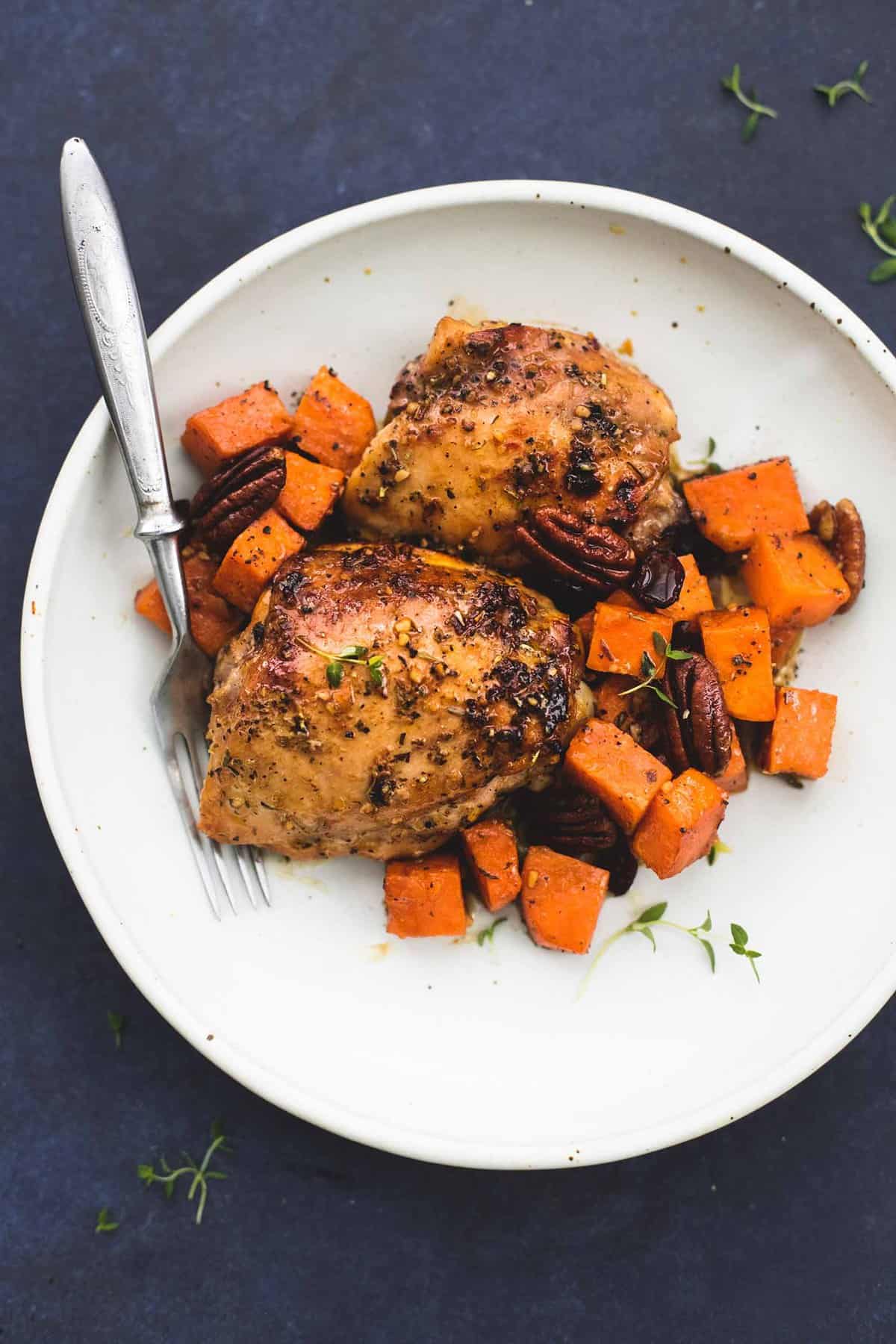 top view of honey roasted chicken and sweet potatoes skillet with a fork on a plate.
