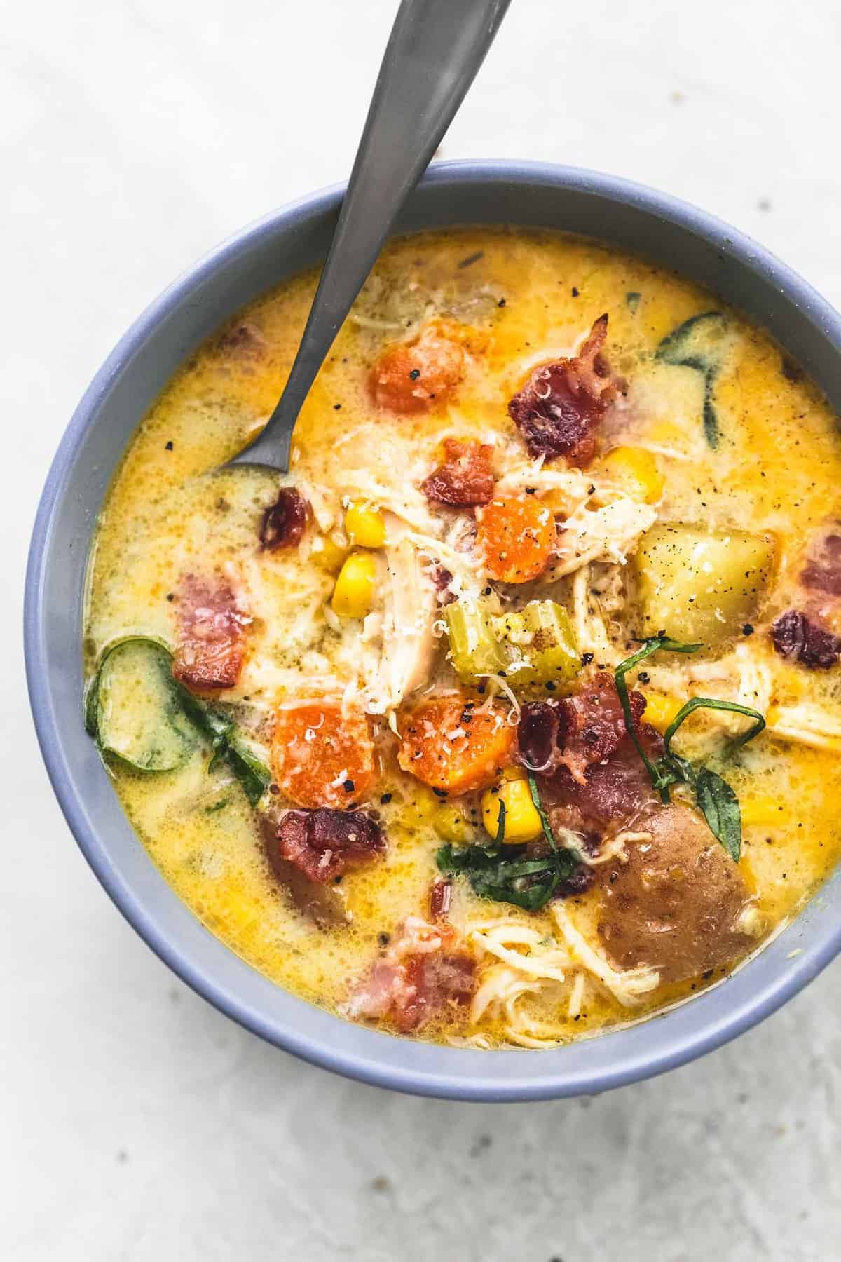 top view of slow cooker New England chicken chowder with a spoon in a bowl.