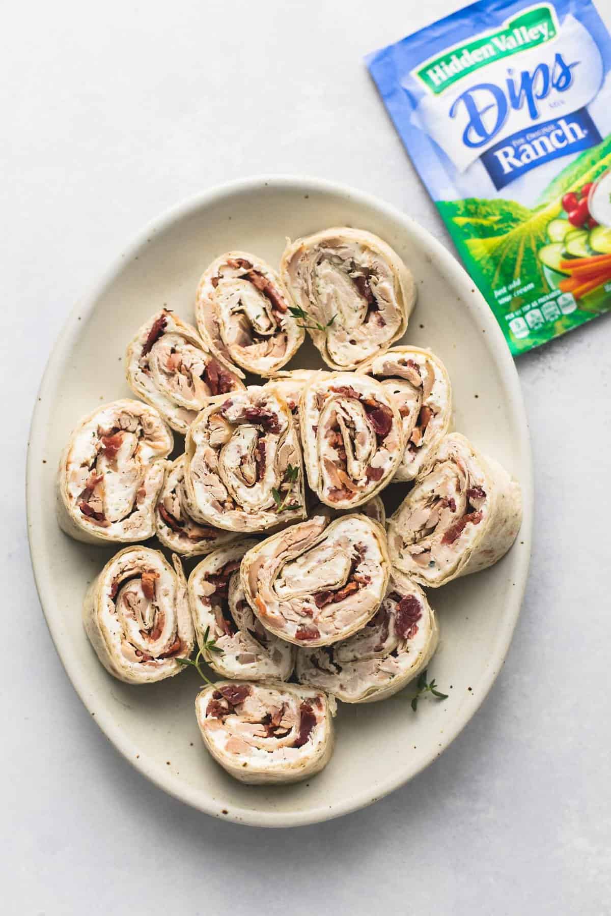 top view of chicken bacon ranch pinwheels on a plate with a ranch packet on the side.