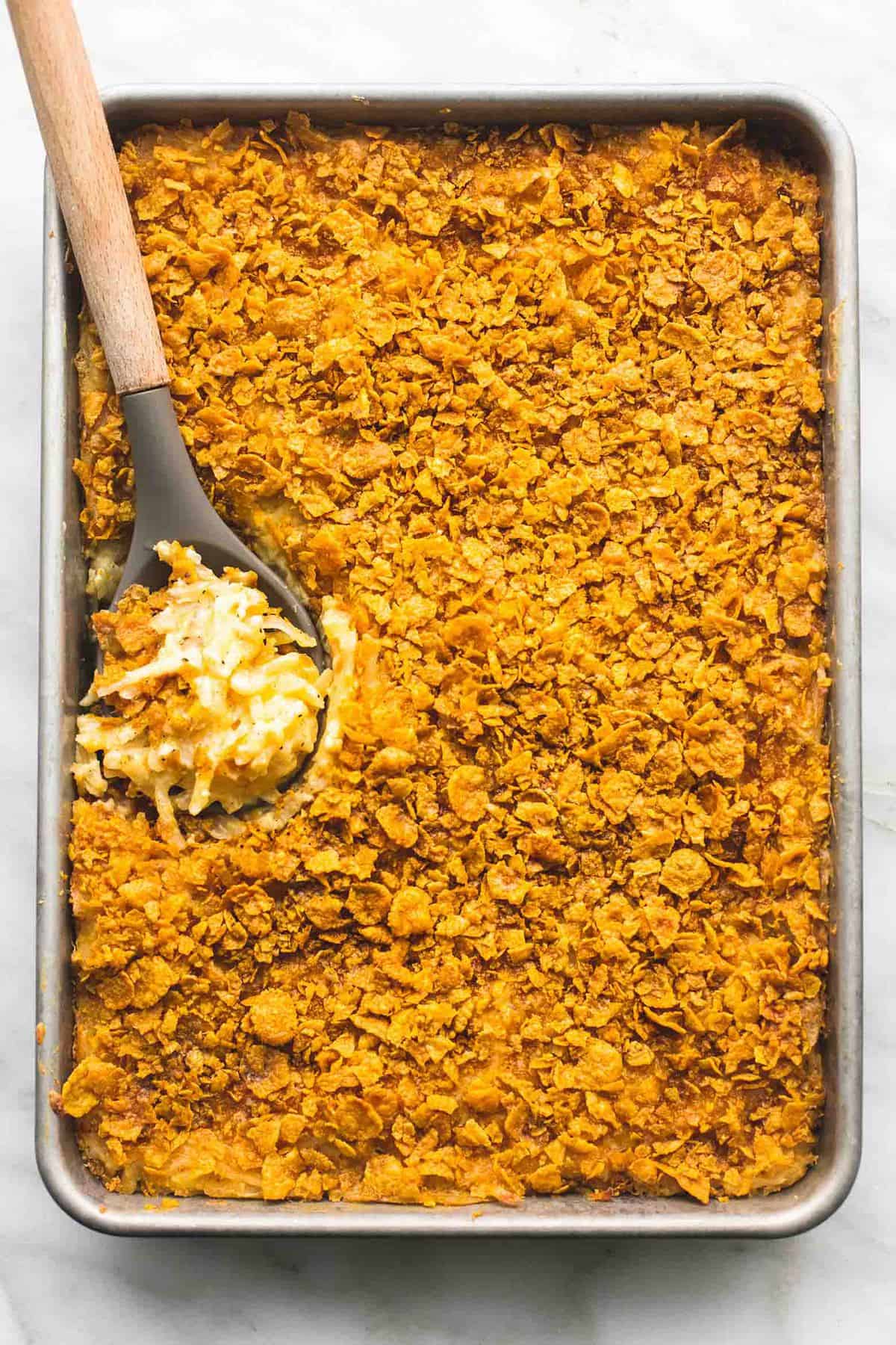 top view of company potatoes with a serving spoon in a baking sheet.