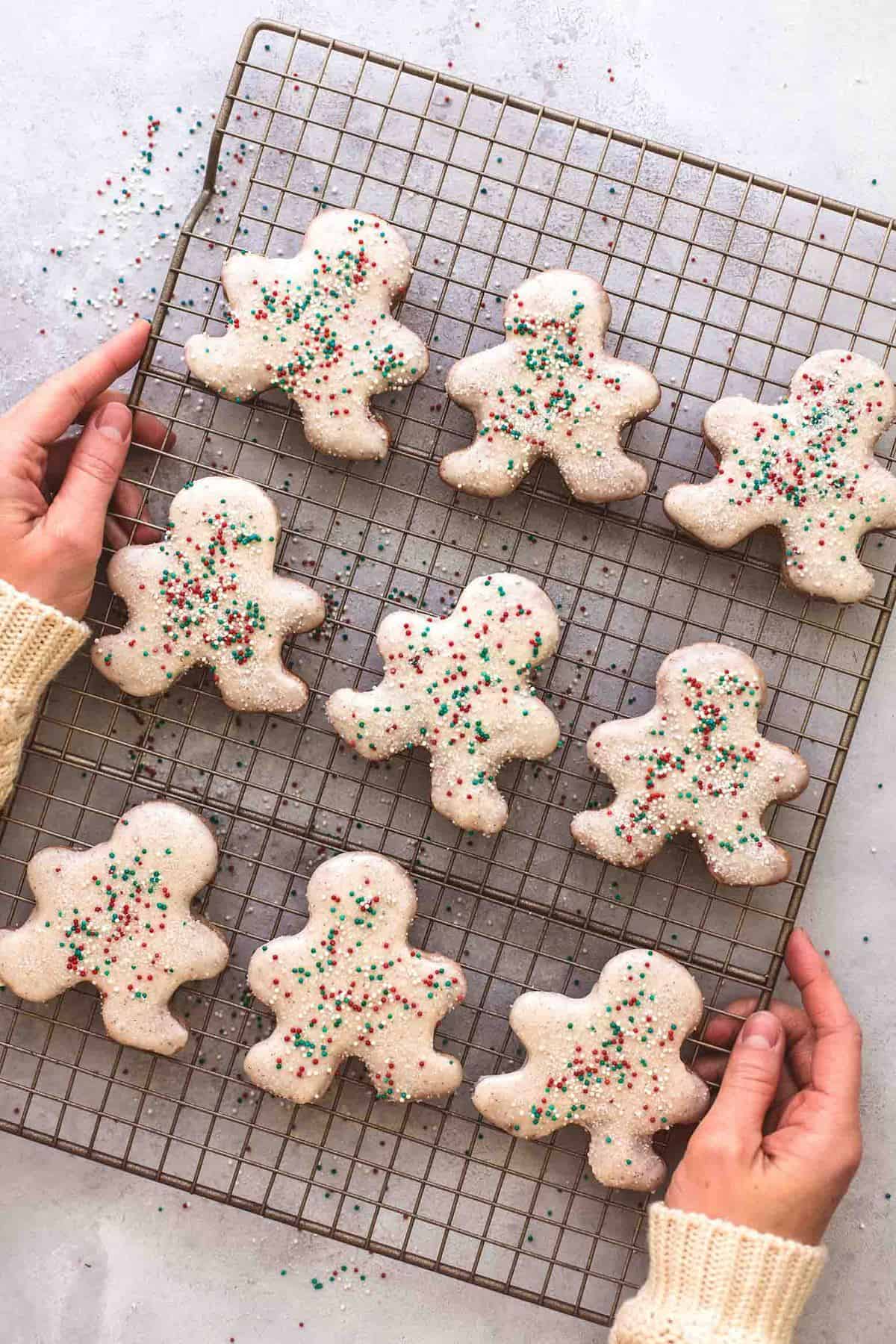 top view of hands holding a cooling rack of gingerbread sugar cookies.