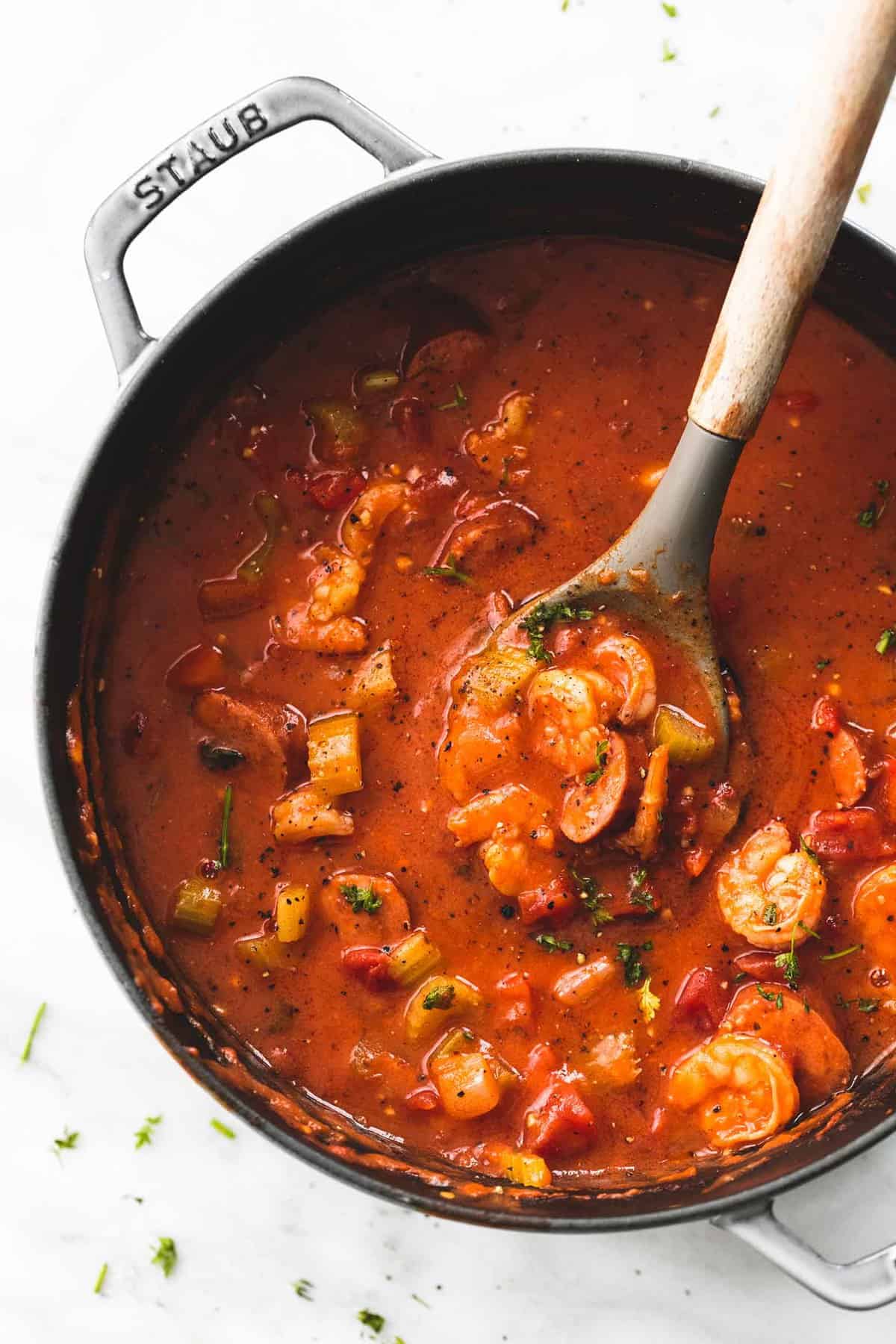 top view of shrimp and sausage gumbo with a serving spoon in a pan.