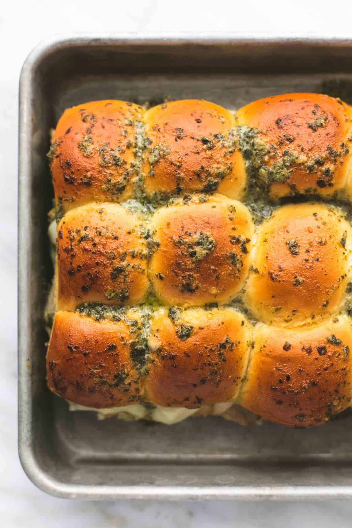 close up top view of pesto mozzarella chicken sliders on a baking sheet.