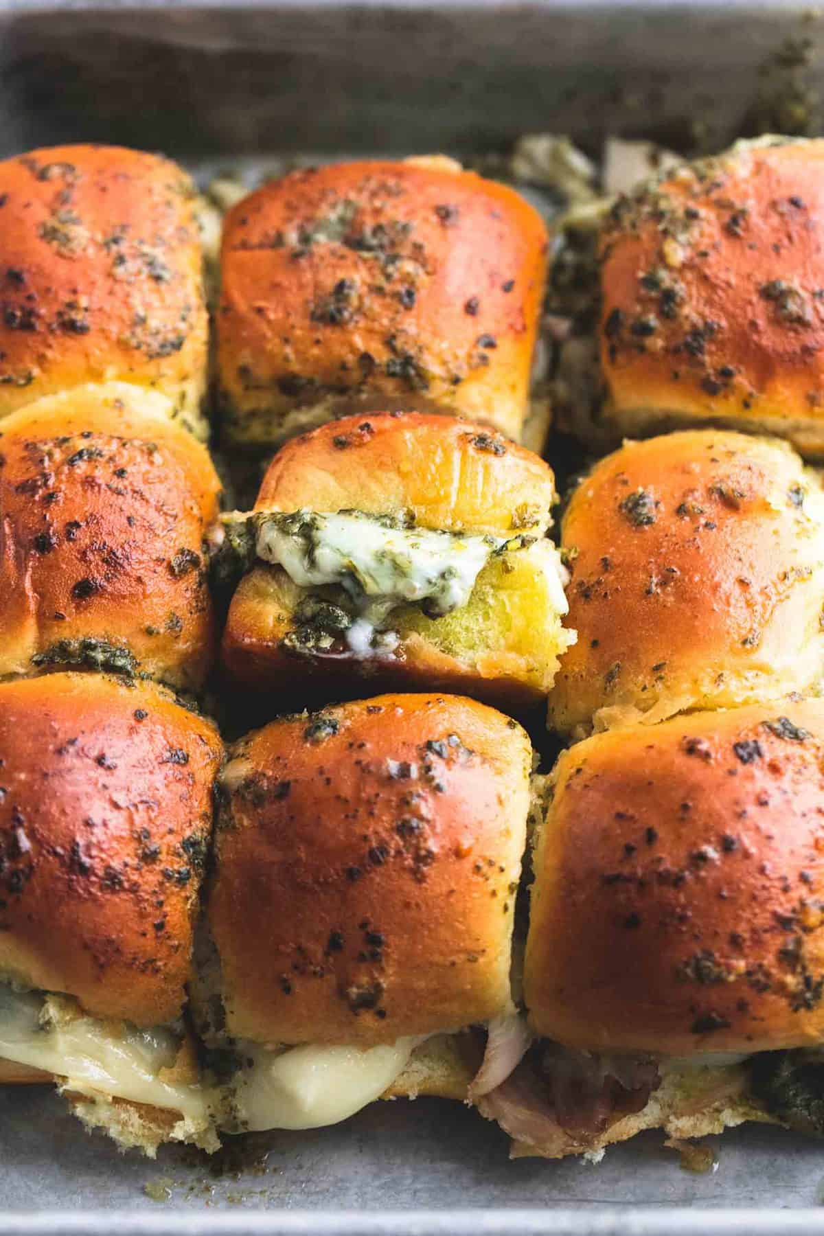 close up of pesto mozzarella chicken sliders on a baking sheet.