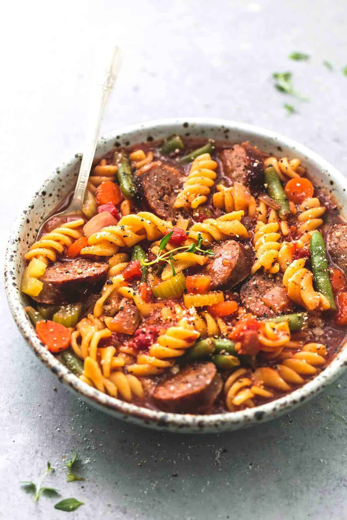 sausage and vegetable soup with a spoon in a bowl.