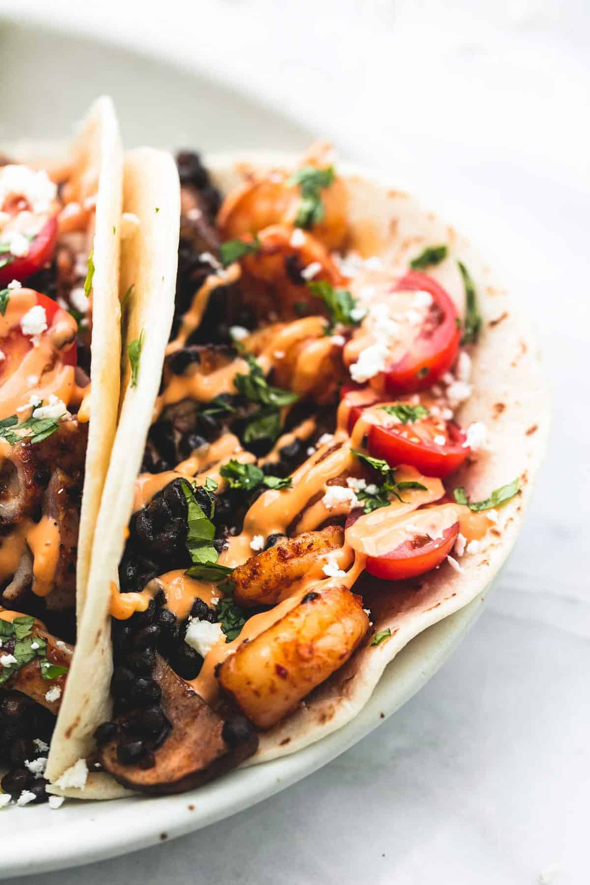 close up of shrimp or chicken and lentil tacos on a plate.