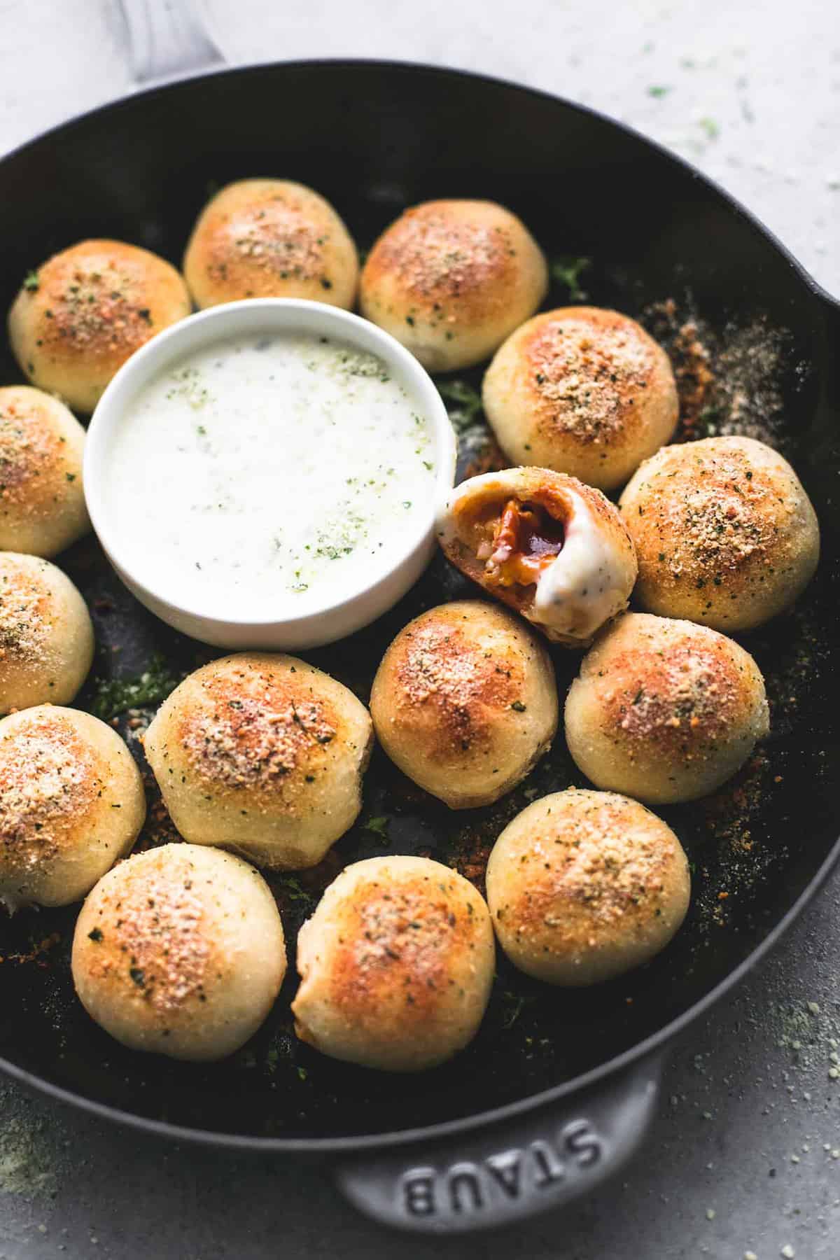 bbq chicken bites with one missing a bite around a bowl of dipping sauce all in a pan.