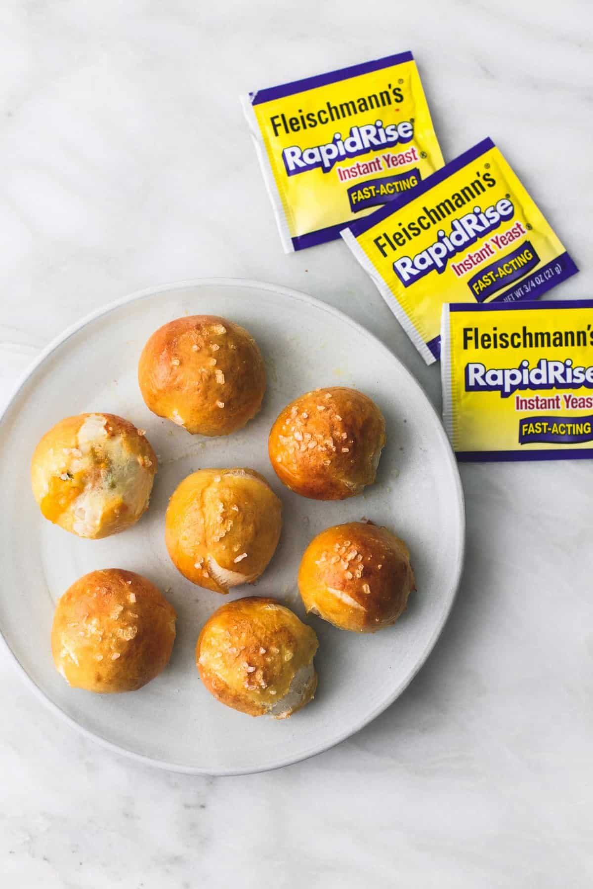 top view of cheddar jalapeño pretzel bites on a plate with yeast packets on the side.