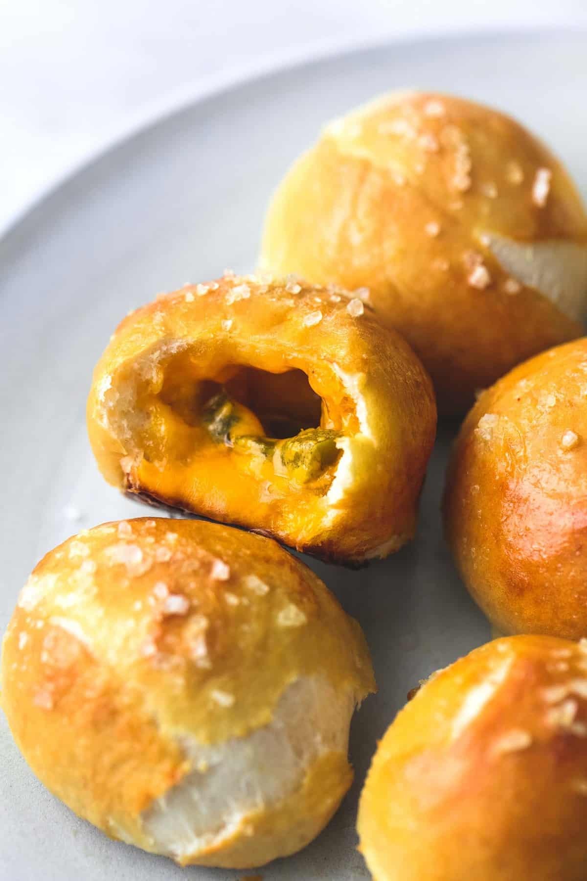close up of cheddar jalapeño pretzel bites on a plate with one missing a bite.