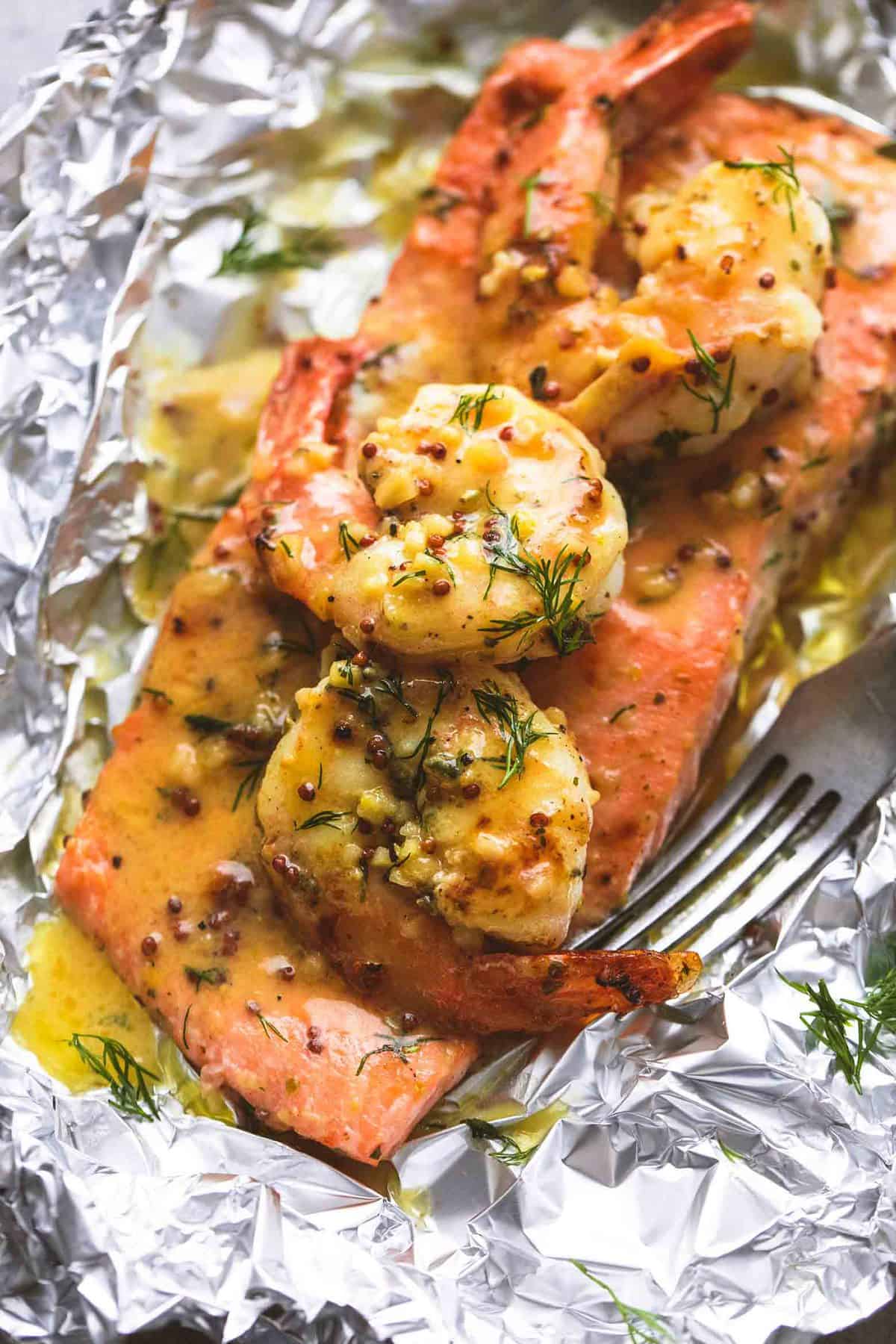 close up of a garlic dijon shrimp & salmon foil pack with a fork.