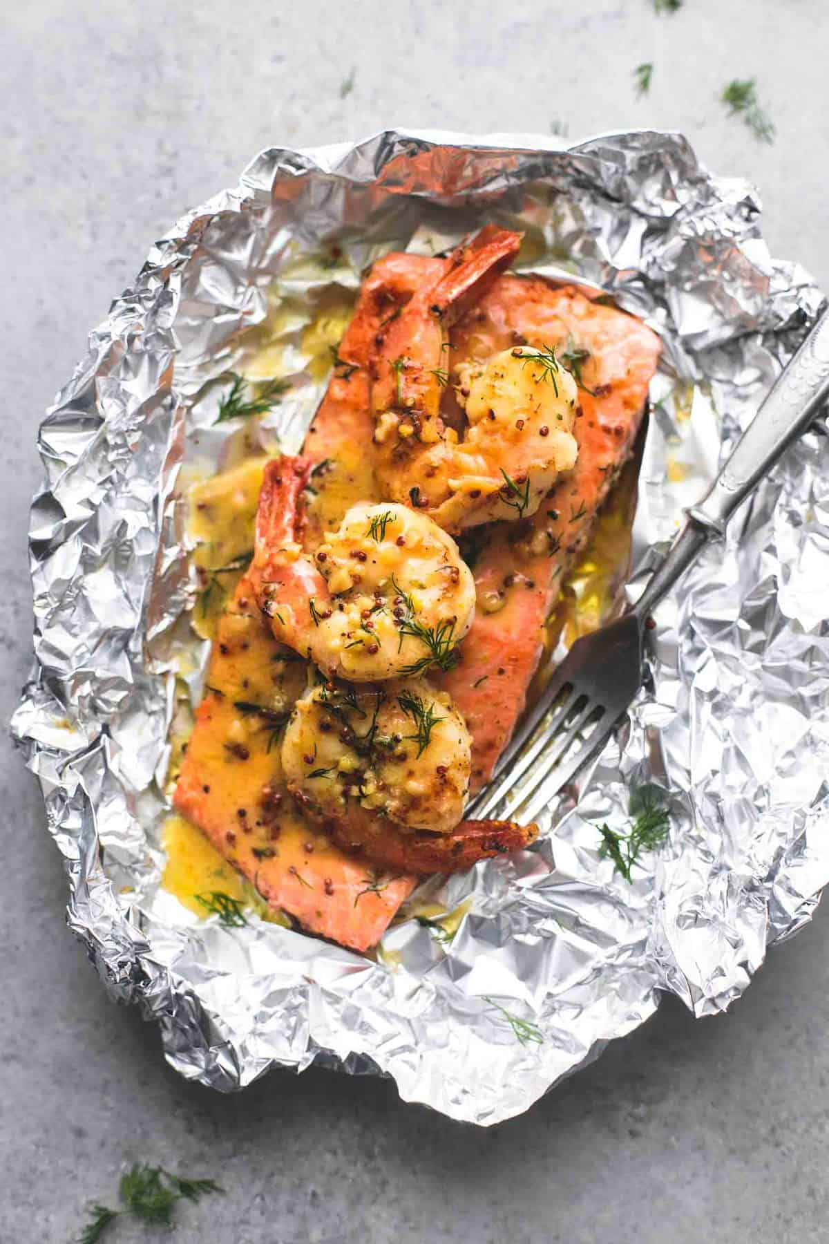 top view of a garlic dijon shrimp & salmon foil pack with a fork.