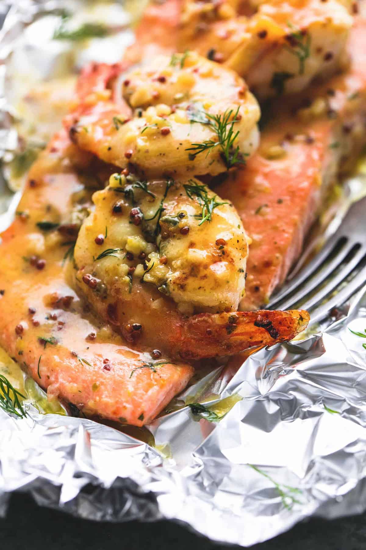close up of a garlic dijon shrimp & salmon foil pack with a fork.
