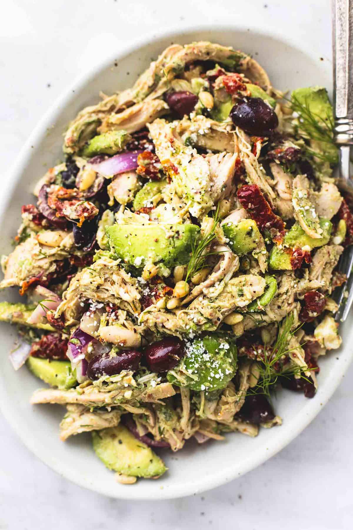 close up top view of Greek avocado chicken salad with a fork on a platter.