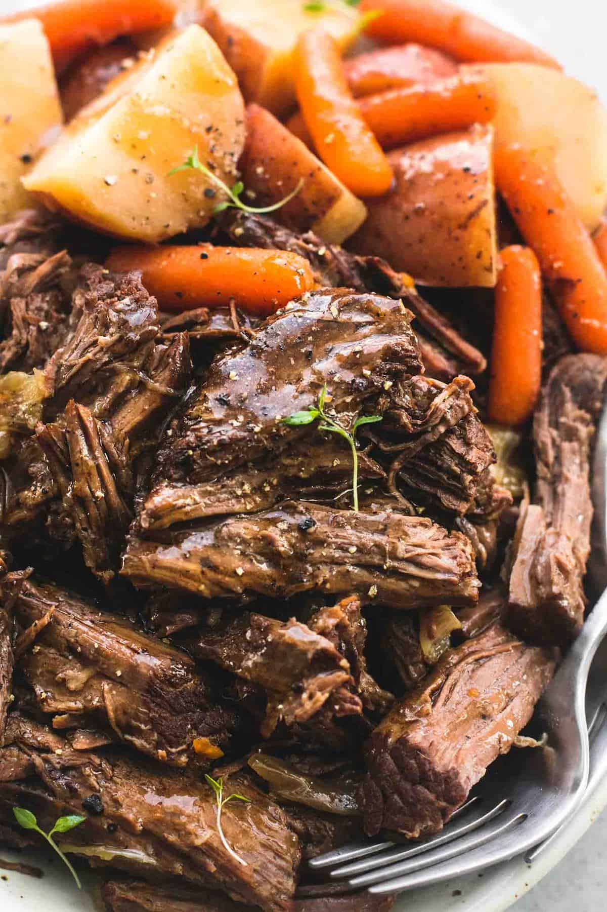 close up of instant pot pot roast and potatoes with a fork on a plate.